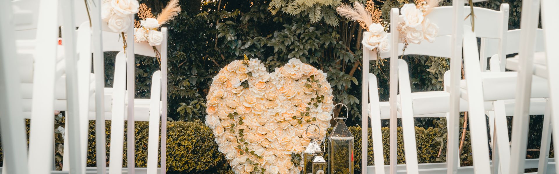 Floral heart wall and white garden chairs styled for a wedding ceremony at Dural Club