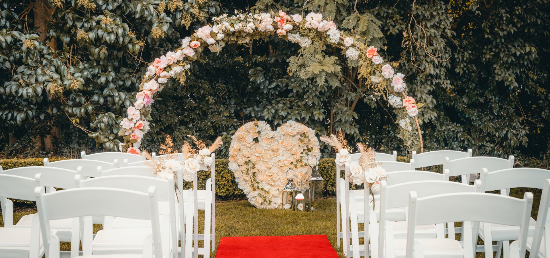 Garden ceremony with floral arch and red carpet aisle at Dural Club