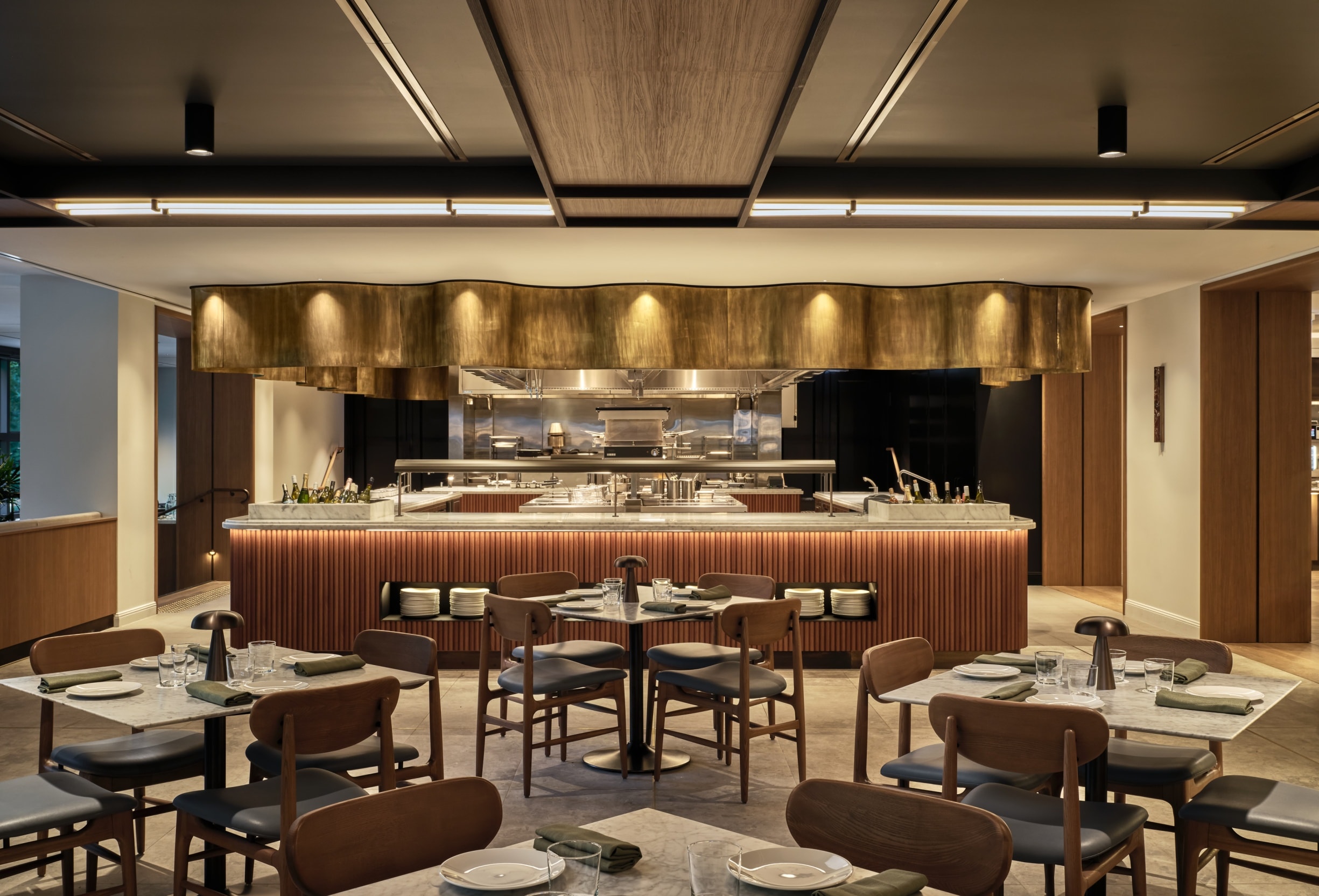 The open woodfire kitchen at Sydney Common beneath a sculptural brass hood