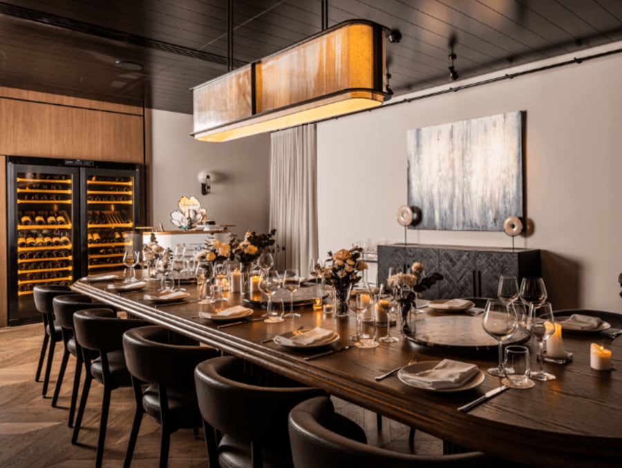The Private Dining Room at Sydney Common, a long timber table lit by a warm pendant, wine fridges and artwork