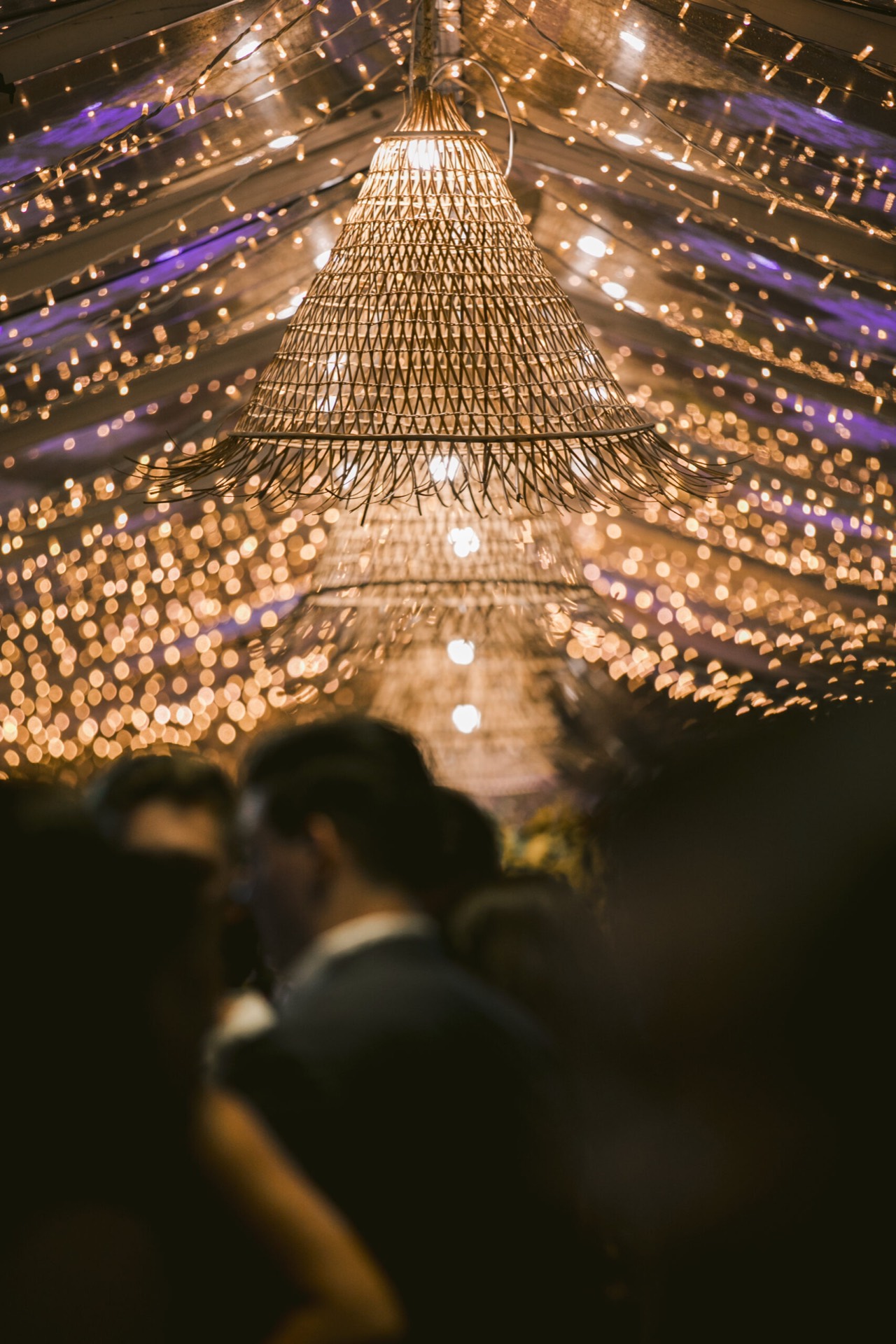 Guests under fairy lights and woven pendant lighting in the marquee at Pier One at night