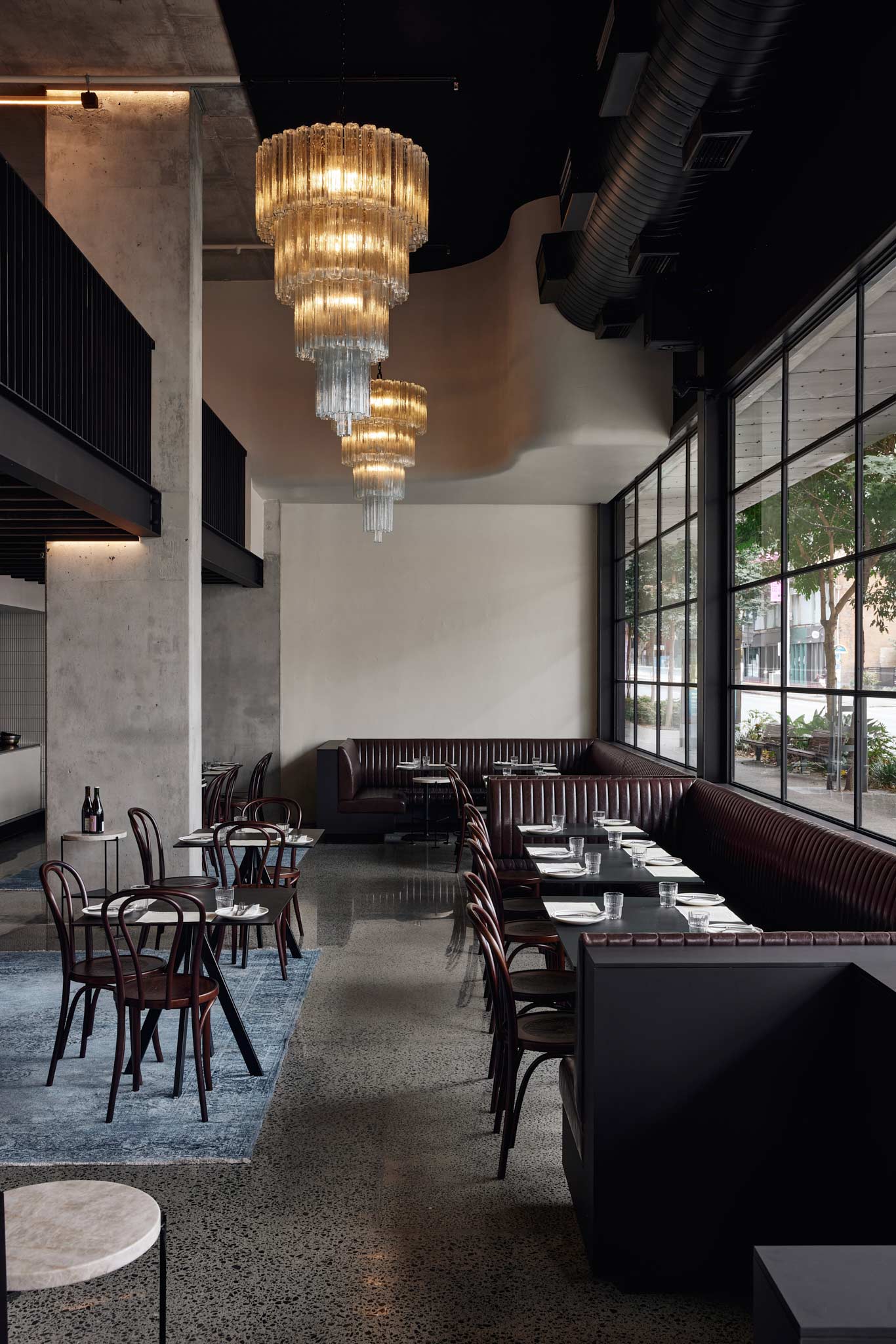Petite's main dining room, with leather banquettes along the window, long tables and a glass chandelier