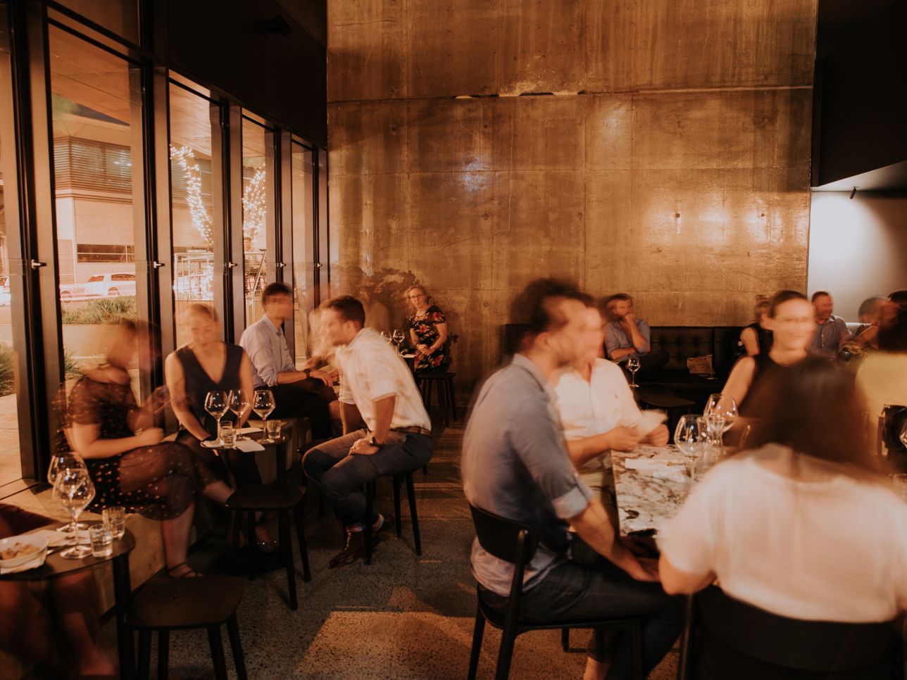 The ground floor main dining room at Snack Man with polished concrete walls, bifold windows open to East Street and guests seated at marble tables