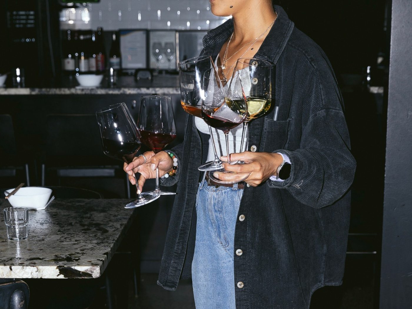 A Snack Man staff member carrying four glasses of wine across the restaurant floor