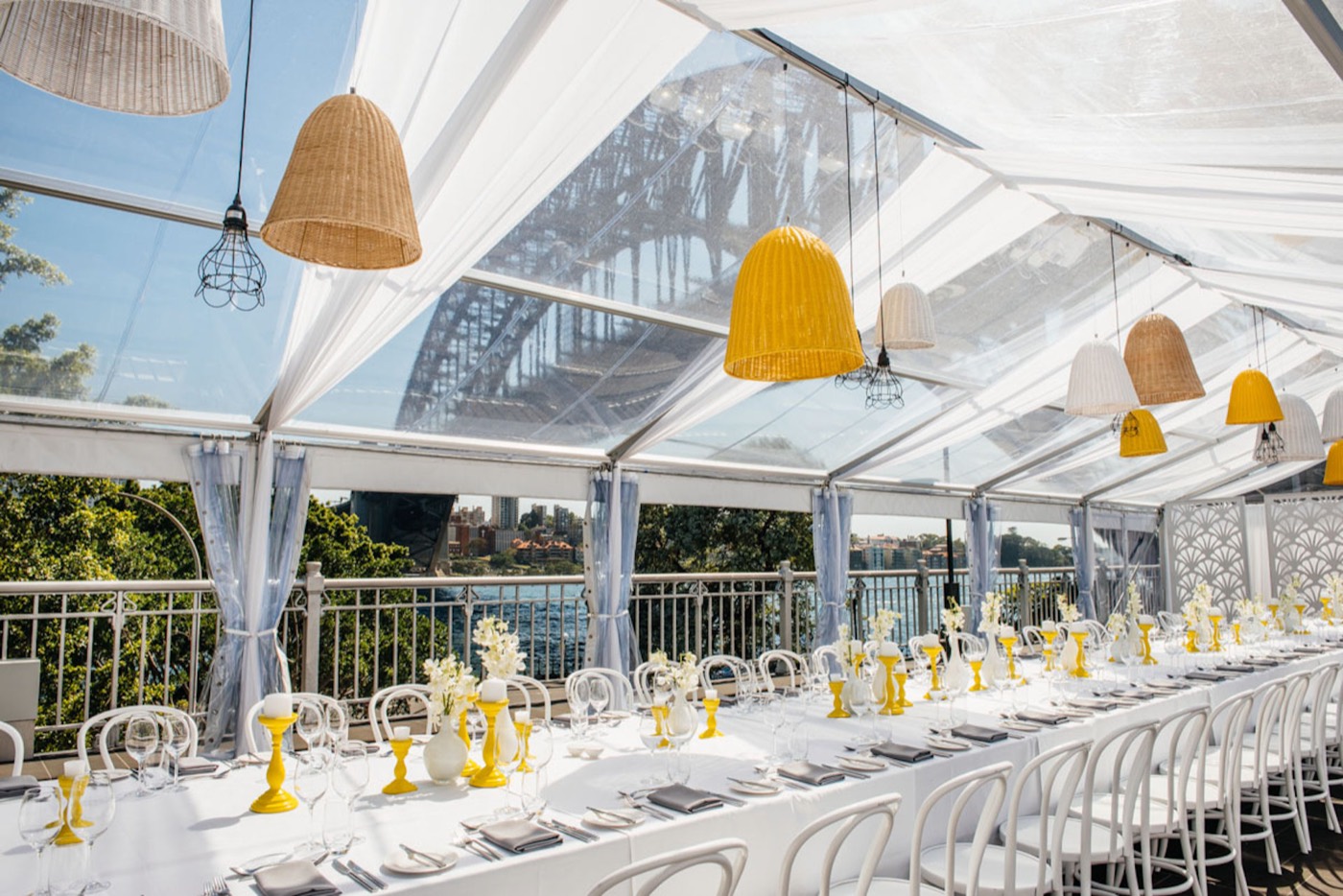 Long banquet table set under the clear-roofed Bridge Marquee at Pier One