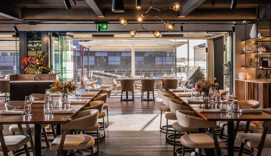 The Dining Room at PIER dining with restaurant seating and folding doors open to the terrace