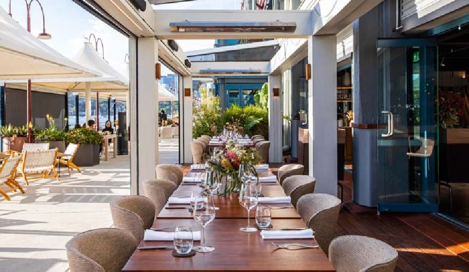 A long Kings Table set on The Terrace at PIER dining under a retractable roof with overhead heaters