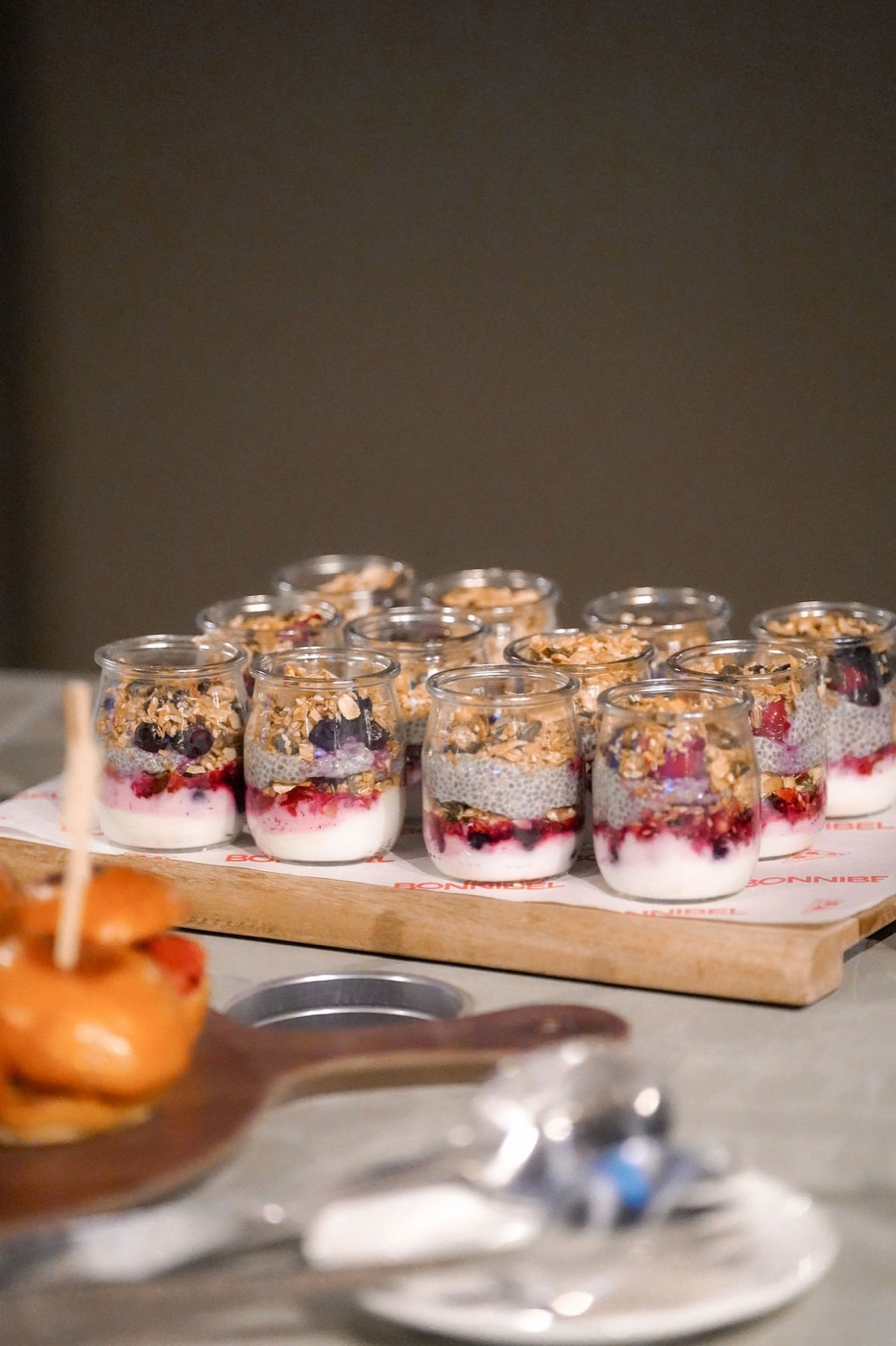 Dessert jars with granola and berries on a catering board